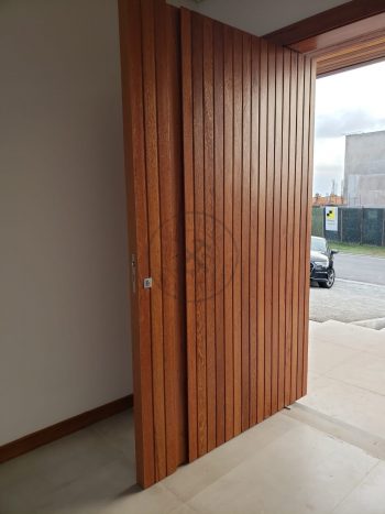 Porta pivotante de lambril de Angelin Pedra com puxador cava na própria madeira - Imagem 9