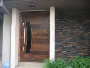 Porta pivotante reforçada com metalon de ferro no interior, revestido com lambril de imbuia, visor de vidro fumê