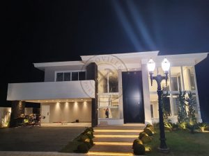 Porta pivotante em ACM preto carbono com um friso vertical e um friso horizontal, bandeira superior e dupla vedação