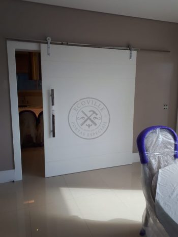 Porta de correr com trilho aparente e revestimento em MDF com pintura laca P.U branco acetinado