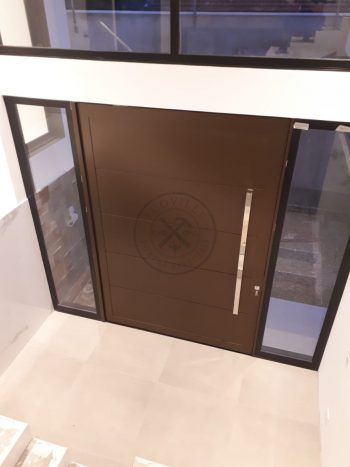 Porta pivotante em ACM bronze com borda e frisos horizontais, painéis de vidro panorâmico e dupla vedação - Imagem 2
