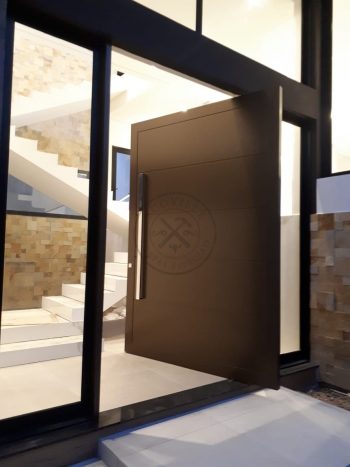 Porta pivotante em ACM bronze com borda e frisos horizontais, painéis de vidro panorâmico e dupla vedação - Imagem 3