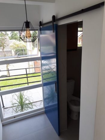 Porta de correr com trilho aparente e revestimento em MDF com pintura laca P.U azul acetinado - Imagem 7