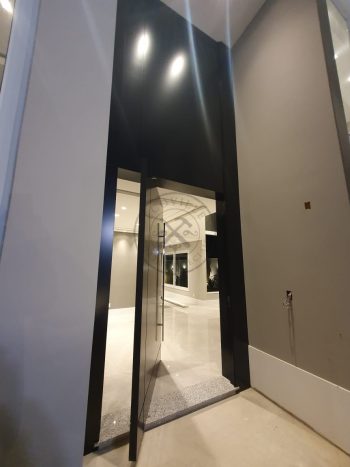 Porta pivotante em ACM preto carbono com um friso vertical e um friso horizontal, bandeira superior e dupla vedação - Imagem 4