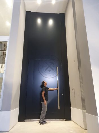 Porta pivotante em ACM preto carbono com um friso vertical e um friso horizontal, bandeira superior e dupla vedação - Imagem 5