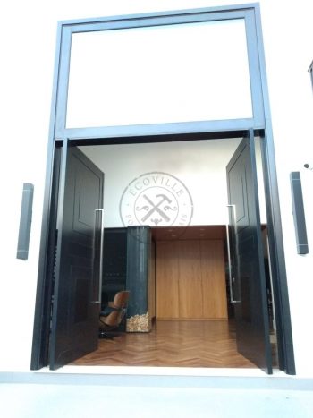 Porta pivotante em ACM preto carbono com almofadas e sistema de abertura dupla com bandeira superior de vidro temperado - Imagem 12