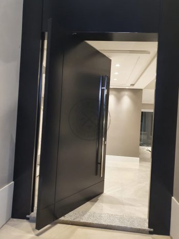 Porta pivotante em ACM preto carbono com um friso vertical e um friso horizontal, bandeira superior e dupla vedação - Imagem 7