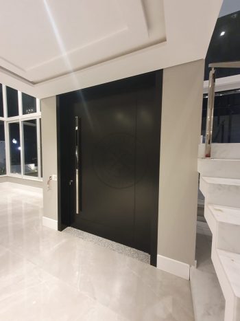 Porta pivotante em ACM preto carbono com um friso vertical e um friso horizontal, bandeira superior e dupla vedação - Imagem 8