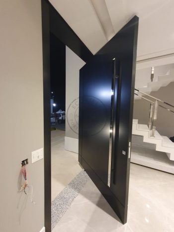 Porta pivotante em ACM preto carbono com um friso vertical e um friso horizontal, bandeira superior e dupla vedação - Imagem 9