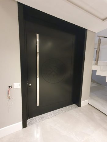 Porta pivotante em ACM preto carbono com um friso vertical e um friso horizontal, bandeira superior e dupla vedação - Imagem 11