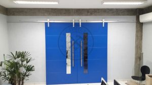 Porta de correr com trilho aparente e revestimento em MDF com pintura laca P.U azul acetinado