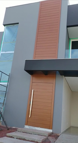 Porta pivotante em ACM amadeirado com bandeira superior e frisos horizontais com dupla vedação