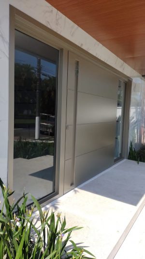 Porta pivotante em ACM Silver Gold com frisos horizontais, puxador cava, portal duplo lateral com vidro 10 mm incolor e dupla vedação - Imagem 3