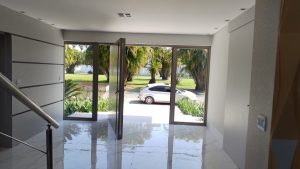 Porta pivotante em ACM Silver Gold com frisos horizontais, puxador cava, portal duplo lateral com vidro 10 mm incolor e dupla vedação - Imagem 6
