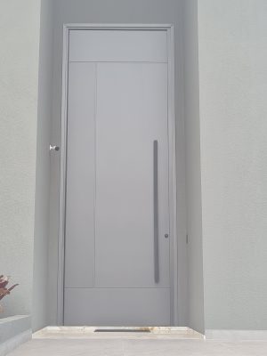 Porta pivotante em ACM com um  friso vertical e dois horizontais, cor cinza com dupla vedação