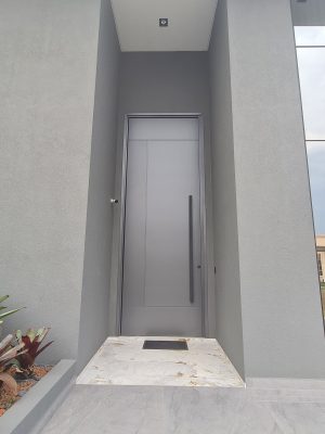 Porta pivotante em ACM com um  friso vertical e dois horizontais, cor cinza com dupla vedação - Imagem 2
