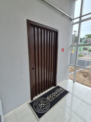 Porta pivotante em ACM Sucupira, modelo ripado na vertical com dupla vedação - Imagem 3