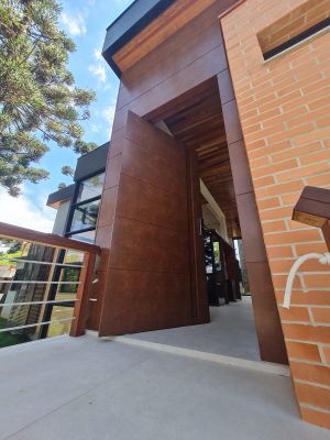 Porta pivotante em ACM aço corten com frisos horizontais, puxador cava e dupla vedação - Imagem 2