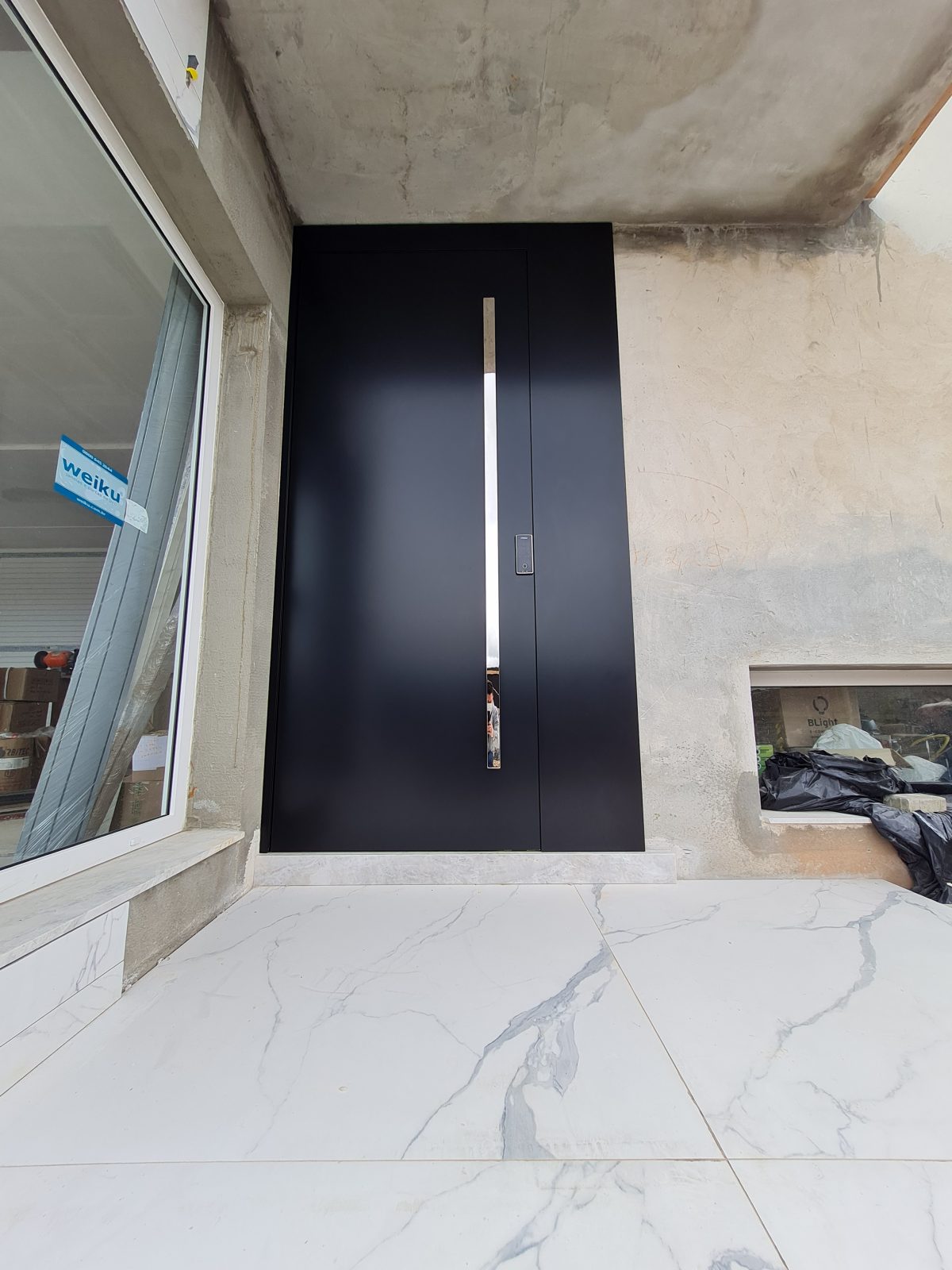 20211111_153545 Porta pivotante em ACM preto carbono, painel lateral fixo no mesmo alinhamento da porta, puxador exposto de inox com 2 metros cromado e dupla vedação - Imagem 4