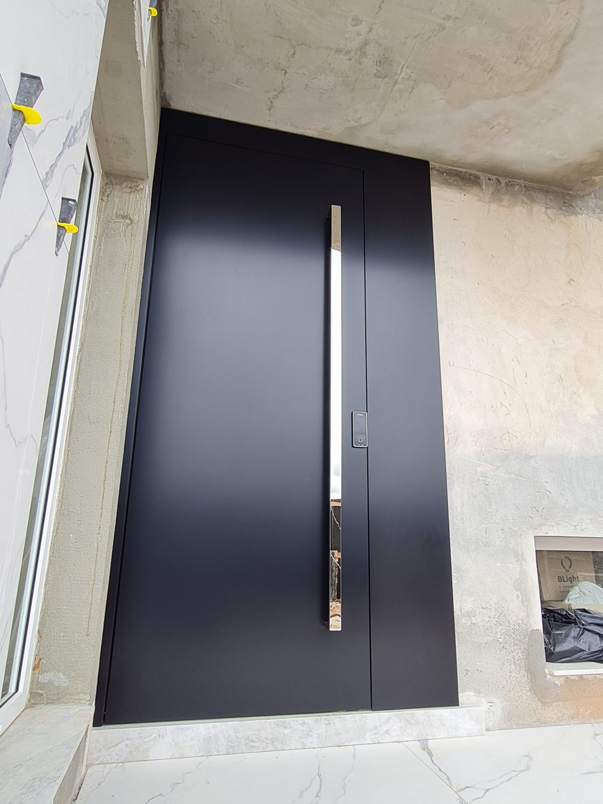 20211111_153837 Porta pivotante em ACM preto carbono, painel lateral fixo no mesmo alinhamento da porta, puxador exposto de inox com 2 metros cromado e dupla vedação - Imagem 1