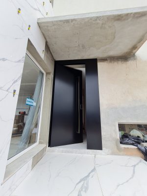 Porta pivotante em ACM preto carbono, painel lateral fixo no mesmo alinhamento da porta, puxador exposto de inox com 2 metros cromado e dupla vedação - Imagem 7