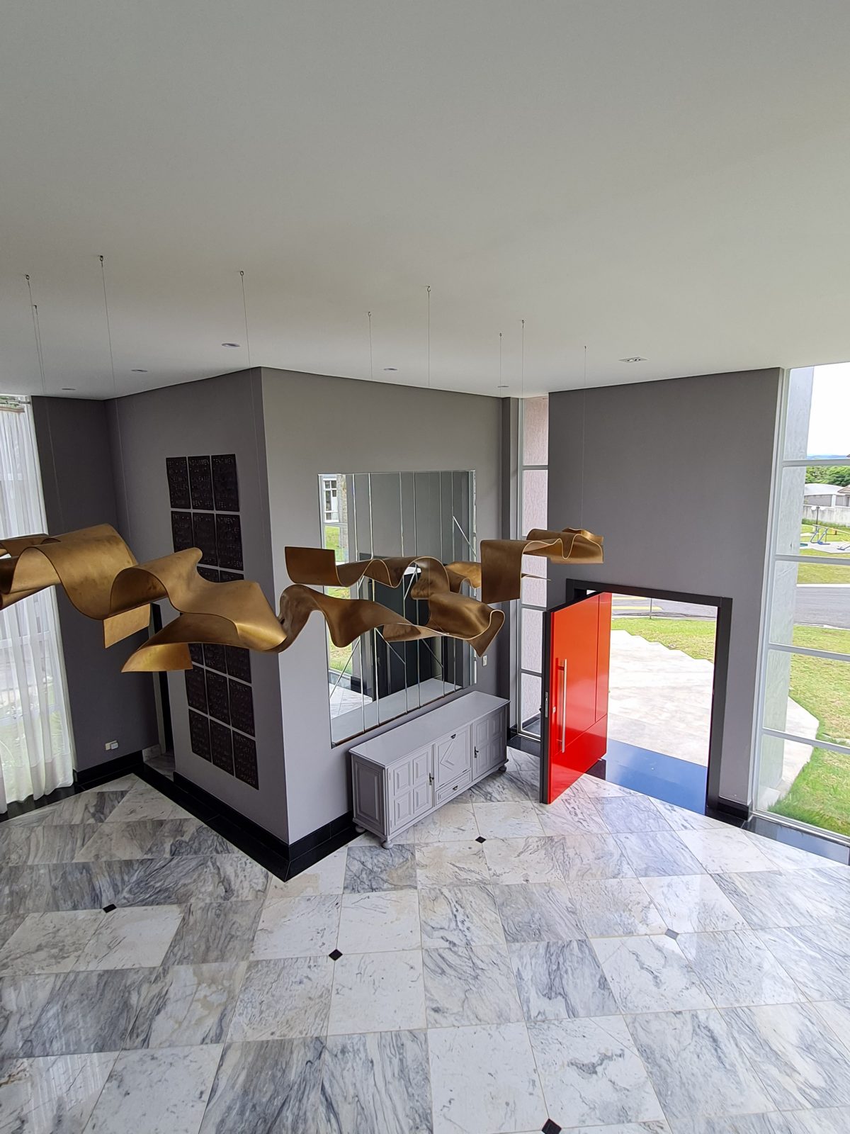 Porta pivotante em ACM com duas cores. Lado externo vermelho fosco e lado interno cinza. Painéis e bandeira fixos seguindo mesmo alinhamento da porta e dupla vedação. - Imagem 7