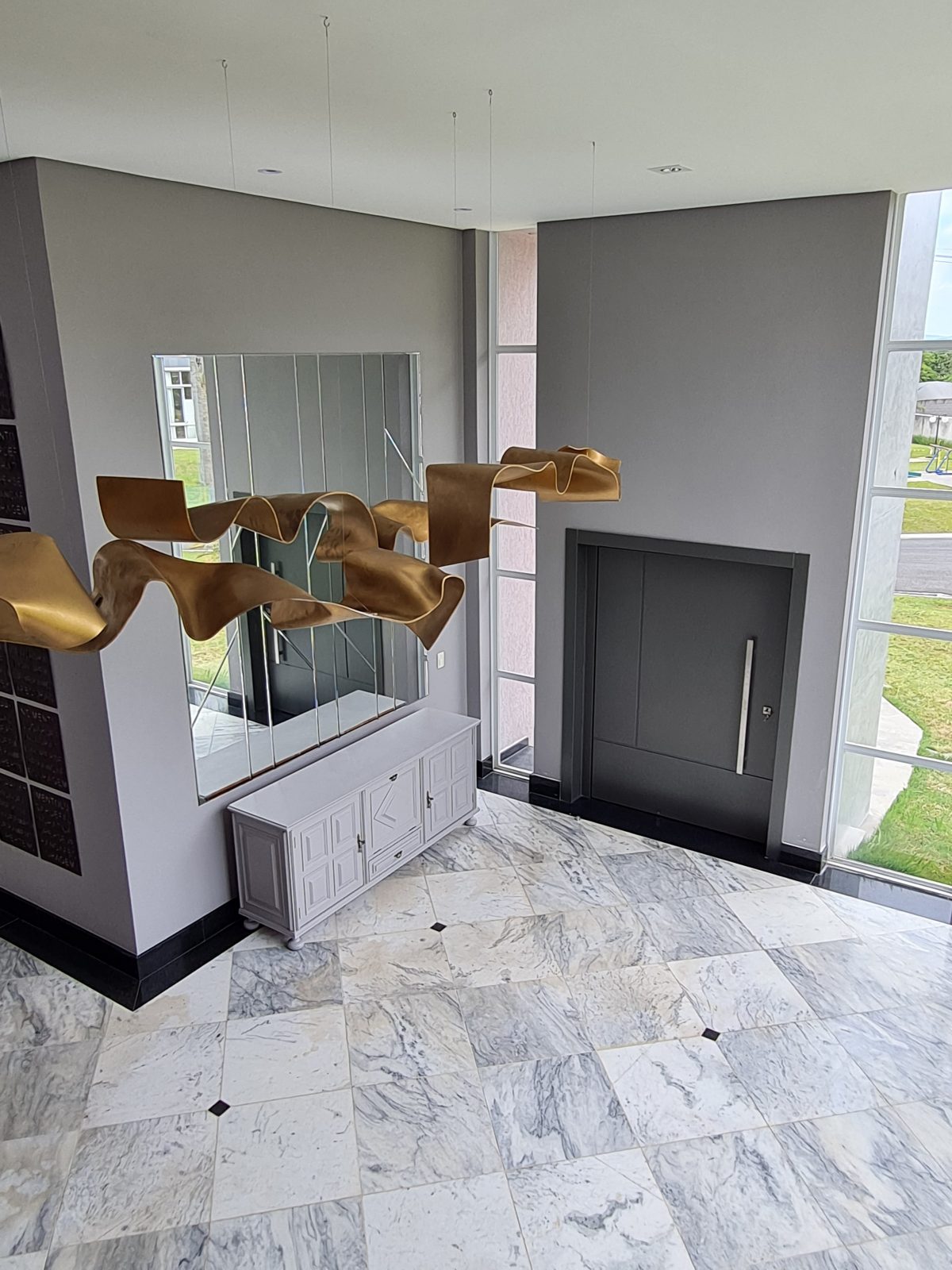 Porta pivotante em ACM com duas cores. Lado externo vermelho fosco e lado interno cinza. Painéis e bandeira fixos seguindo mesmo alinhamento da porta e dupla vedação. - Imagem 8