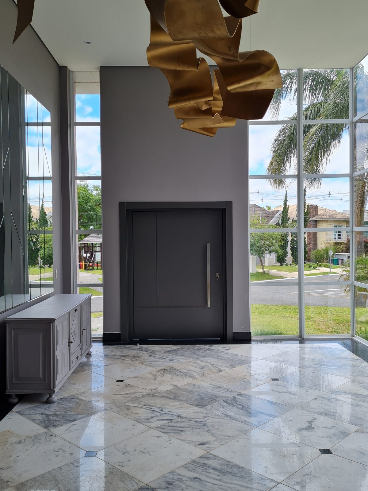 Porta pivotante em ACM com duas cores. Lado externo vermelho fosco e lado interno cinza. Painéis e bandeira fixos seguindo mesmo alinhamento da porta e dupla vedação. - Imagem 9