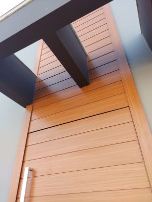 Porta pivotante em ACM amadeirado com bandeira superior e frisos horizontais com dupla vedação - Imagem 5