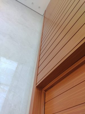 Porta pivotante em ACM amadeirado com bandeira superior e frisos horizontais com dupla vedação - Imagem 8