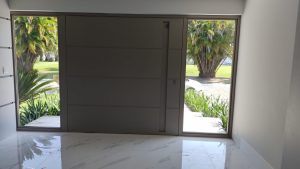 Porta pivotante em ACM Silver Gold com frisos horizontais, puxador cava, portal duplo lateral com vidro 10 mm incolor e dupla vedação - Imagem 7