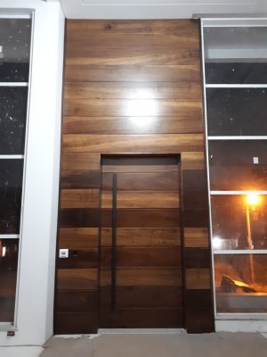 Porta pivotante com estrutura de aço no interior, revestido com lambril maciço de Imbuia