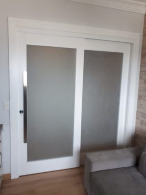 Porta com sistema de correr embutido com vidro panorâmico jateado, pintura laca branca acetinado