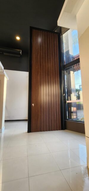 Porta pivotante em ACM ripado na vertical cor Sucupira e dupla vedação - Imagem 2