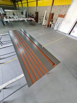 Porta pivotante em ACM Dark Gray, ripado na vertical em ACM mogno, puxador cava com LED, dupla vedação porta e batente - Imagem 4