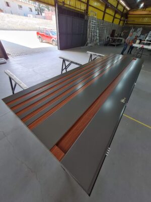 Porta pivotante em ACM Dark Gray, ripado na vertical em ACM mogno, puxador cava com LED, dupla vedação porta e batente - Imagem 6