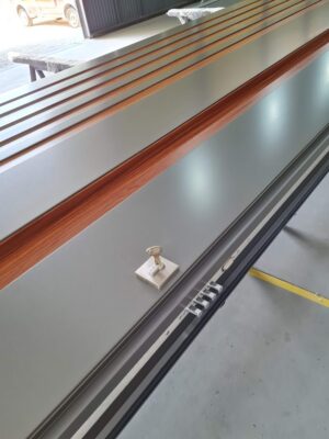 Porta pivotante em ACM Dark Gray, ripado na vertical em ACM mogno, puxador cava com LED, dupla vedação porta e batente - Imagem 10