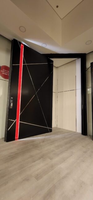 Porta em pivotante em ACM preto fosco modelo BBB com puxador cava vermelho com LED, dupla vedação porta e batente