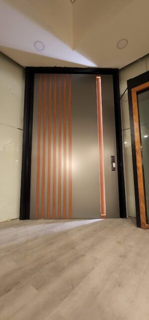 Porta pivotante em ACM Dark Gray, ripado na vertical em ACM mogno, puxador cava com LED, dupla vedação porta e batente