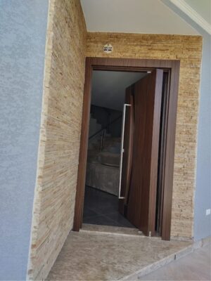 Porta pivotante em ACM madeirado Sucupira, modelo com vidro curvo fume, dupla vedação porta e batente - Imagem 3