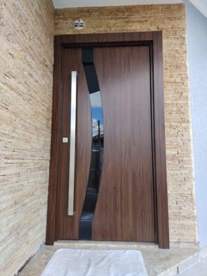 Porta pivotante em ACM madeirado Sucupira, modelo com vidro curvo fume, dupla vedação porta e batente