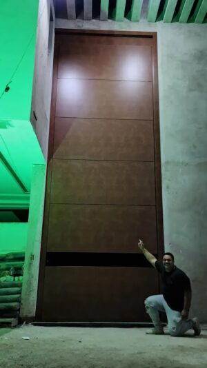 Porta pivotante em ACM com puxador cava em ACM preto fosco na horizontal, dupla vedação porta e batente