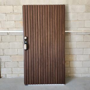Porta pivotante em ACM ripado vertical, chapa Wood Sucupira, puxador cava e dupla vedação