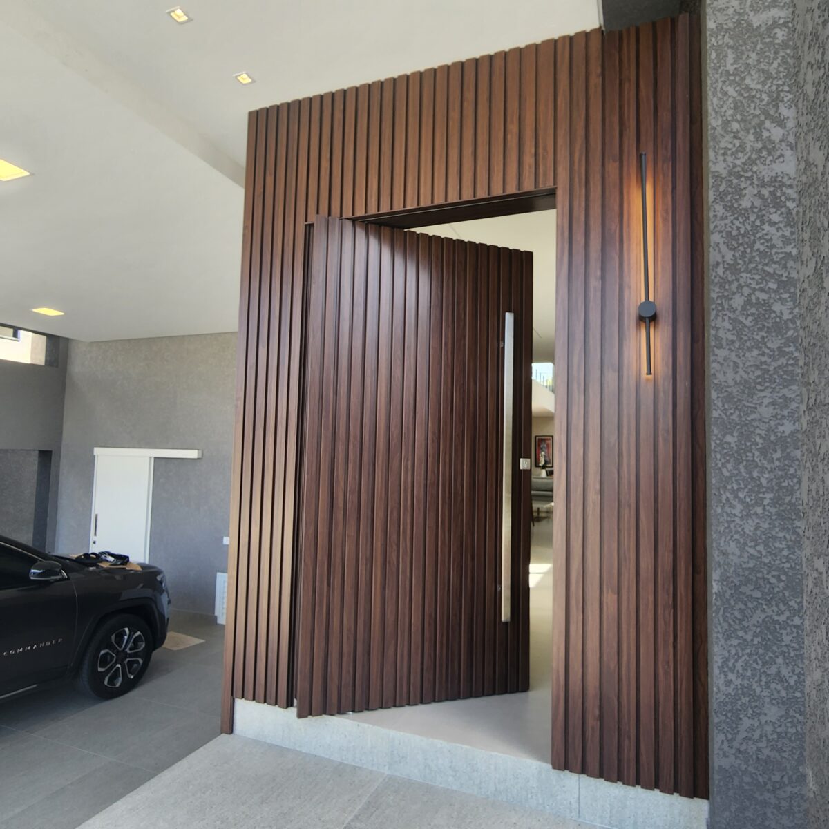 20230202_095732 Porta pivotante em ACM ripado na vertical, painéis ripado seguindo alinhamento da porta, chapa Wood Sucupira - Imagem 7