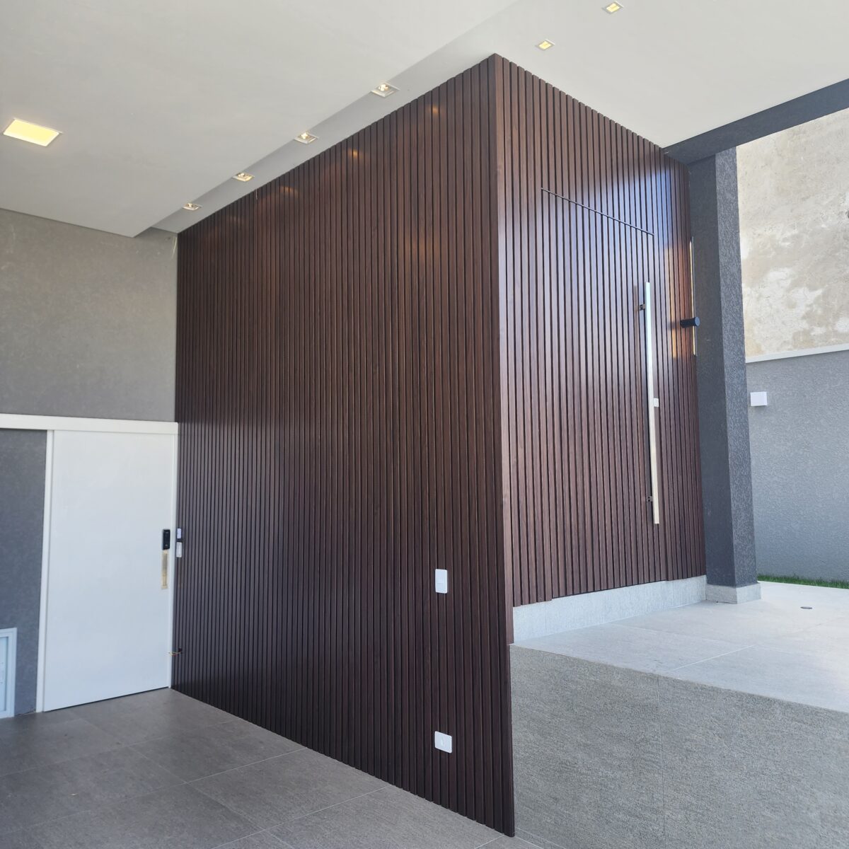 20230202_095843 Porta pivotante em ACM ripado na vertical, painéis ripado seguindo alinhamento da porta, chapa Wood Sucupira - Imagem 1