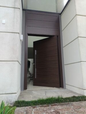 Porta pivotante em ACM, chapa Wood Sucupira, bandeira superior fixa