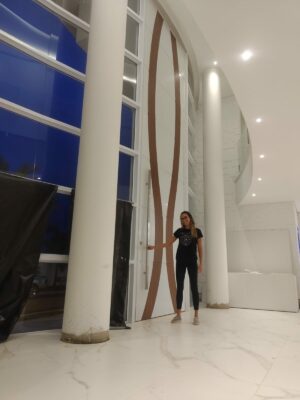 Porta pivotante em ACM branco neve com detalhe em mogno e dupla vedação porta e batente