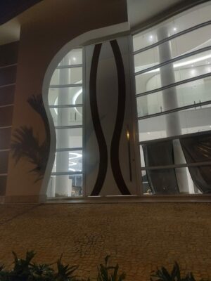 Porta pivotante em ACM branco neve com detalhe em mogno e dupla vedação porta e batente - Imagem 7