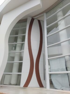 Porta pivotante em ACM branco neve com detalhe em mogno e dupla vedação porta e batente - Imagem 5