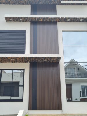 Porta pivotante em ACM Wood Sucupira com detalhe em ACM preto